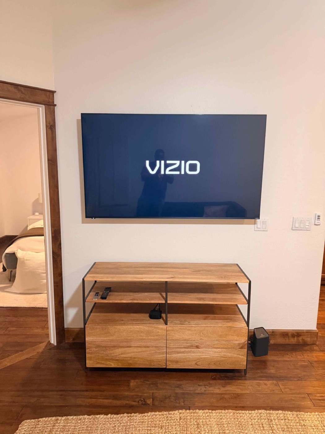 A TV mounted level above a wood media console